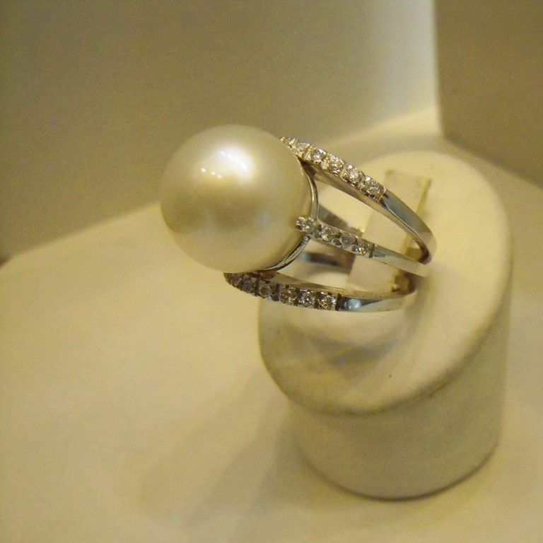 Anello in oro bianco750/000 , formato da tre fedine di brillantini che sostengono una perla australiana.